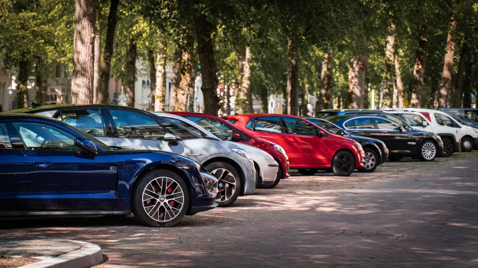 Voitures garées en rang sur un parking arboré