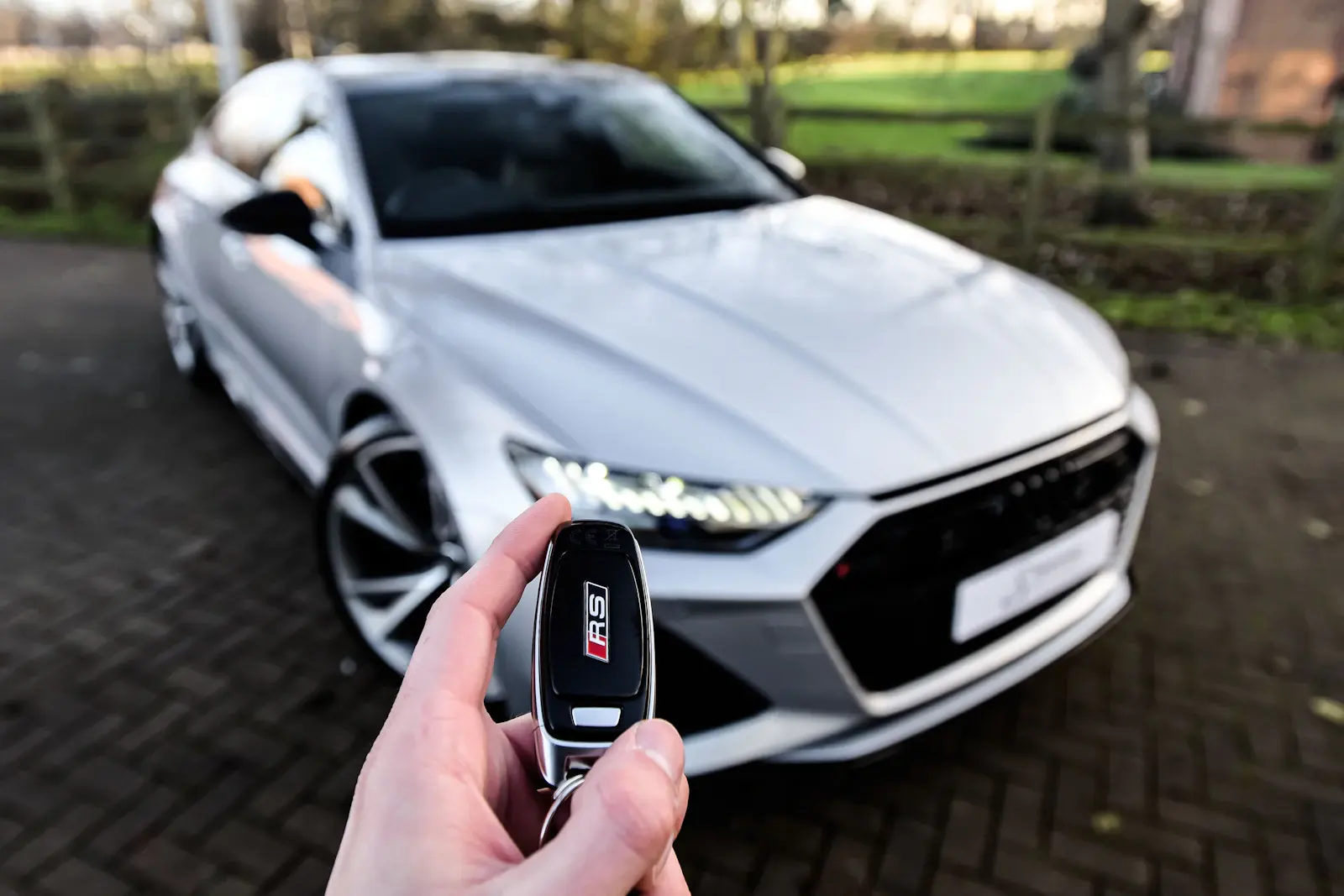 Clé de voiture tendue devant une berline grise