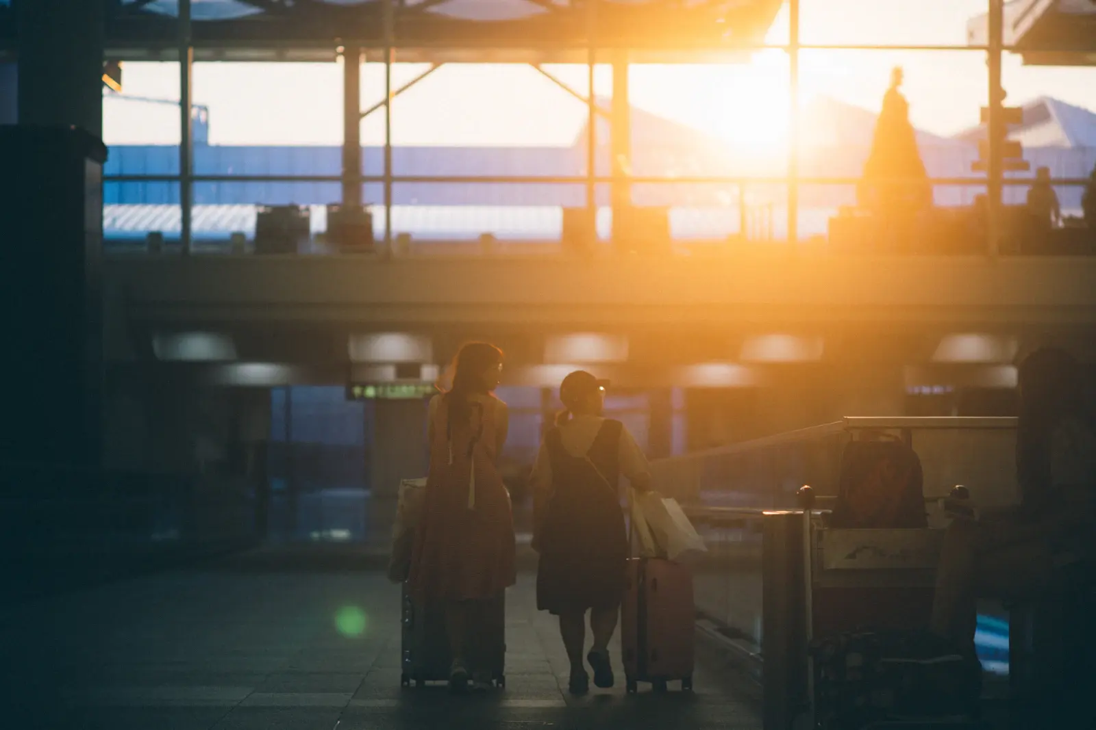 Deux voyageuses avec leurs valises dans un terminal au coucher du soleil
